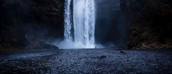 Rear view of man standing by waterfall