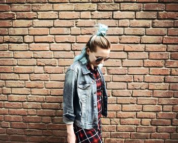 Full length of teenage girl standing against brick wall