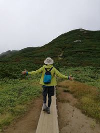 Rear view of man standing on mountain against sky