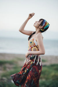 Side view of young woman wearing hat standing at beach