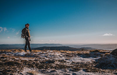 Man standing on mountain against blue sky