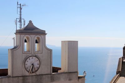 Clock tower by sea against clear sky