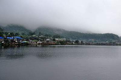 Scenic view of lake by buildings against sky