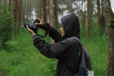 Full length of man photographing in forest