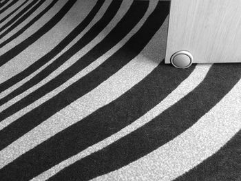 High angle view of a small wheel under a removable desk on a stripped carpet 