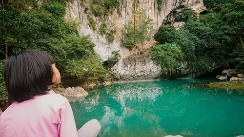 Rear view of girl standing by lake against mountain