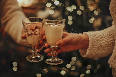 Midsection of woman holding wineglass on table