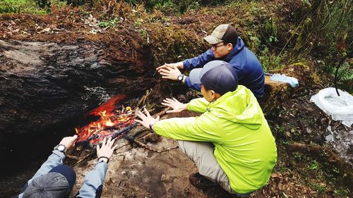 People hands over bonfire in forest
