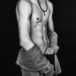 Midsection of shirtless man standing against black background