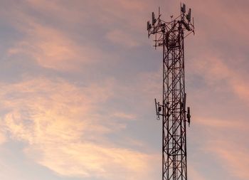 Low angle view of silhouette communications tower against sky during sunset