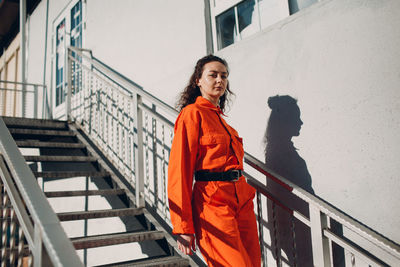 Portrait of young woman standing against railing