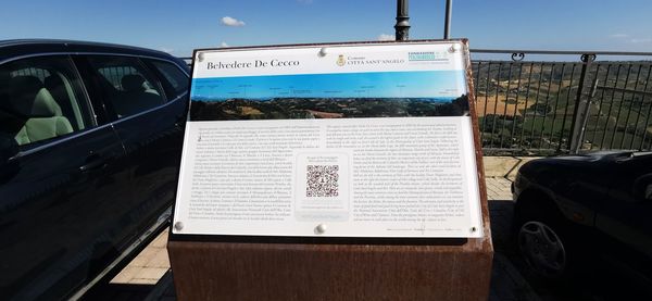 Information sign on road in city against sky