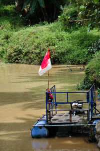 Red flag on river against trees