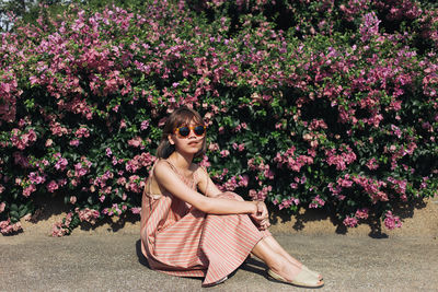 Portrait of young woman with pink flowers at park