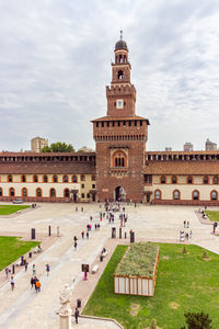 Group of people in front of historical building against sky