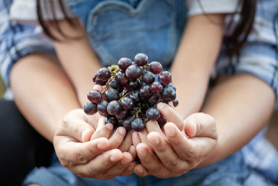 Midsection of couple holding grapes while sitting outdoors