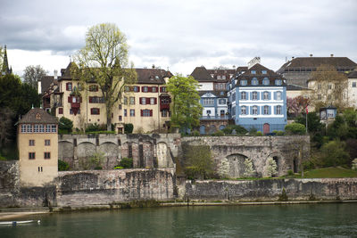 Buildings by river against sky