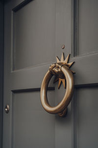 Close up of a metal door knocker on a wooden front door of a house.