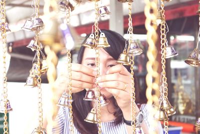 Close-up of woman fixing bells hanging on chain