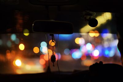 Close-up of illuminated lights seen through car windshield at night