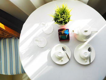 Directly above shot of cup and saucers with teapot on table at home