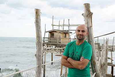 Portrait of bald man standing on pier over sea
