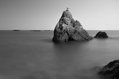 Rock formation in sea against clear sky