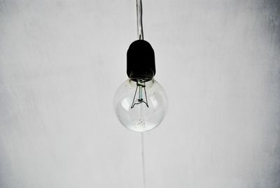 Close-up of light bulb hanging over white background