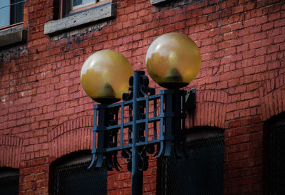 Low angle view of street light against brick wall