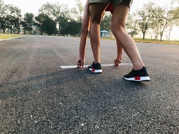 Low section of man skateboarding on road