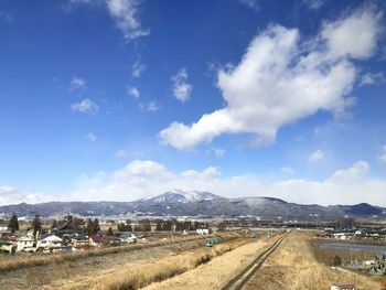 Road amidst field against blue sky