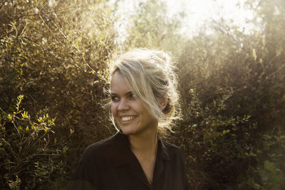 Smiling woman standing against plants