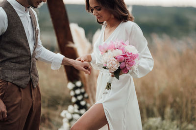 Midsection of couple holding flower