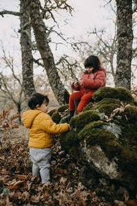 Cute sibling playing in forest during autumn