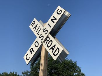 Low angle view of road sign against clear blue sky