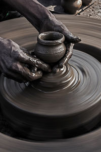 Cropped hands of man molding shape on pottery wheel