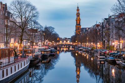 Boats moored in canal amidst buildings in city