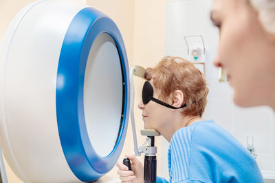 A girl optometrist examines the eyes of a patient using special modern equipment