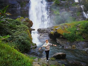 Woman standing by waterfall