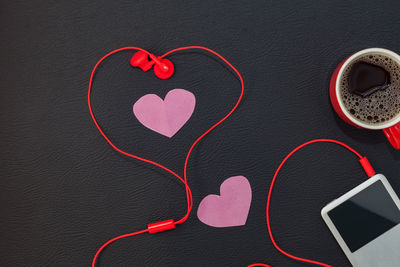 Close-up of red headphones connected to ipod over black background