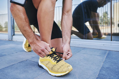 Sportsman tying his shoelaces. he is wearing yellow sneakers. person