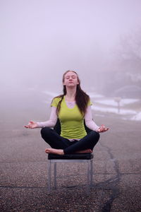 Young woman sitting on chair against the sky