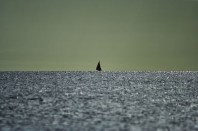 Close-up of sailboat sailing on sea against sky