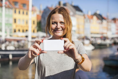 Portrait of happy woman photographing at harbor
