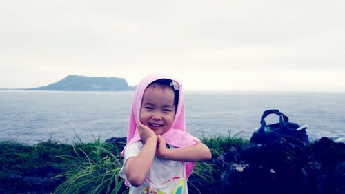 Portrait of smiling girl standing by sea against sky