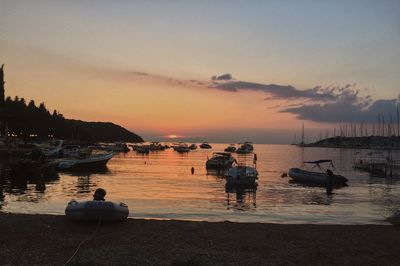 Boats moored on sea against sky during sunset