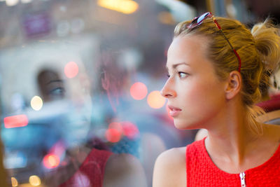 Portrait of young woman looking at illuminated nightclub