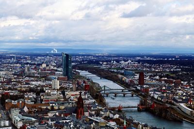 High angle view of city buildings against cloudy sky