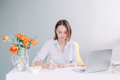 Businesswoman writing on document while sitting in office