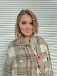 Portrait of smiling young woman standing against wall
